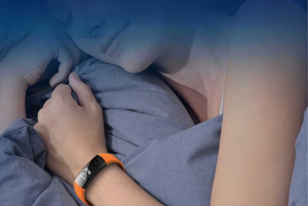 Mulher a dormir com pulseira monitor de atividade no pulso