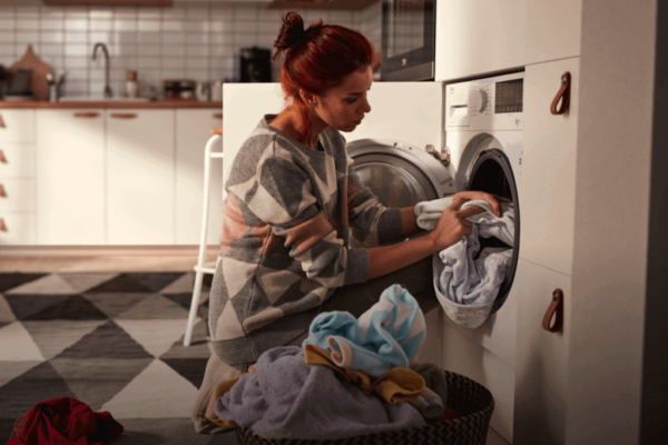 Senhora a colocar a sua roupa numa máquina de lavar ou de secar roupa