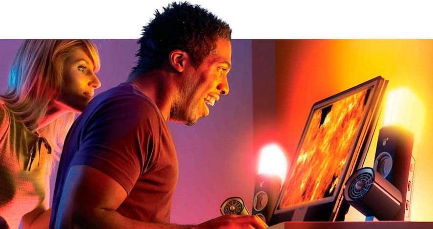 Rapaz a jogar num monitor para jogos de consola com luz quente e rapariga atrás