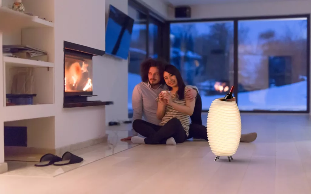 Casal na sala de estar ao lado de uma lareira e com uma Kooduu