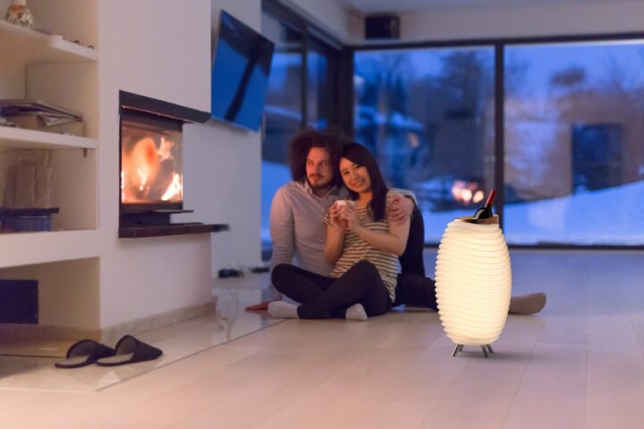 Casal na sala de estar ao lado de uma lareira e com uma Kooduu