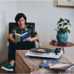 Rapaz a ler com um gira-discos em cima da mesa